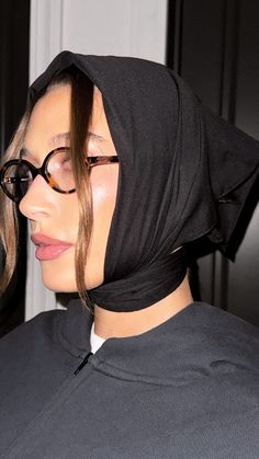 a woman wearing glasses and a black hoodie