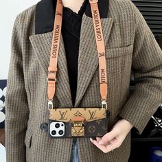 a person wearing a brown jacket and holding a cell phone in their hand with a louis vuitton keychain on it