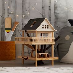 a doll house sitting on top of a wooden table next to a stuffed animal and tree