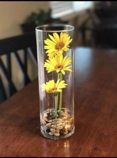 a glass vase filled with yellow flowers on top of a wooden table