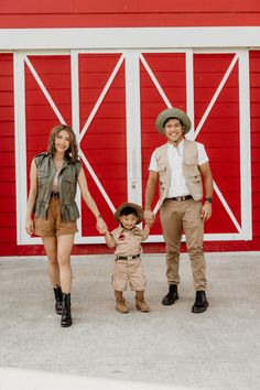 a man, woman and child standing in front of a red barn with the door open