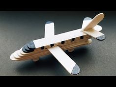 a toy airplane made out of wood on a gray surface with black dots around the wings