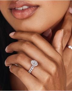 a close up of a person wearing an engagement ring and holding her hand near her face