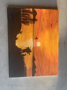 a painting on the side of a building with birds flying over it and an orange sunset