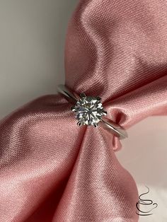 a diamond ring sitting on top of a pink cloth