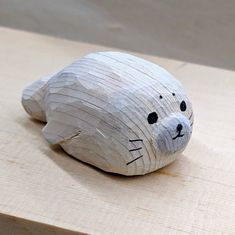 a white bear made out of wood sitting on top of a piece of plywood