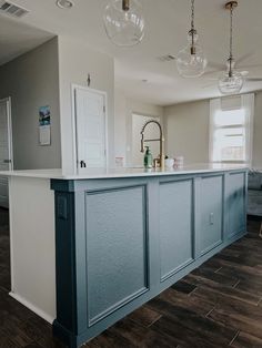 an empty kitchen with blue cabinets and white counter tops in the middle of a living room