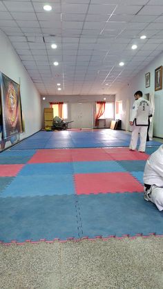 two men are practicing karate in an empty room with blue and pink mats on the floor