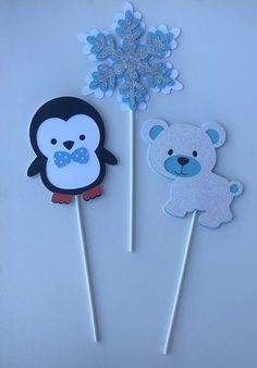 two cupcake toppers with frosting on them, one penguin and the other bear