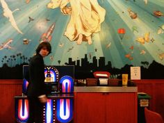 a woman standing in front of a machine with an image on the wall behind her