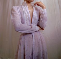 Vintage sheer lavender prairie dress by Gunne Sax. Features dainty florals on sheer striped fabric, delicate lace trims and cuffs, slight puff sleeves, pearlescent buttons on cuffs, textured translucent buttons along the center, hook closure on waist, and attached waist sash. Entire garment is sheer. Era: Circa 1970s Condition: Excellent; There is a small repair on the left shoulder and the 4th button from the top has been replaced - courtesy of the previous owner. The last button is missing and the faintest dot on the shoulder. Size: No label, but estimated for an adult XXS or may suit junior sizing Color: Lavender, white, pink, green Brand: Gunne Sax Measurements: 15.75in pit to pit, 13.75in shoulder to shoulder, 23.5in sleeve length, 11.75in waist, 39in length Fabric Content: No label, Waist Sash, Dress Wedding Guest, Green Brands, Gunne Sax, Lace Trims, Prairie Dress, Striped Fabric, Dress Wedding, Fashion History