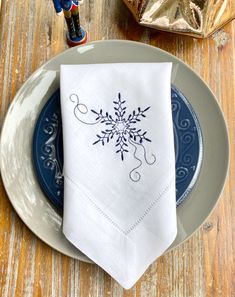 a white napkin with a blue snowflake design on it sitting on a plate