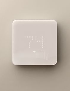 an electronic clock on the wall with numbers and symbols written in white letters that spell out time