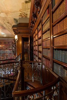 an old library with many books on the shelves and stairs leading up to the second floor