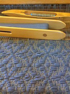 two wooden scissors sitting on top of a blue cloth covered tablecloth next to a pair of scissors