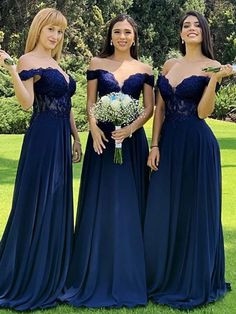 three bridesmaids in blue dresses posing for the camera with one holding her bouquet