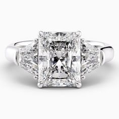 a three stone diamond ring with two princess cut diamonds in the center and side stones on each