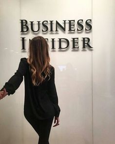 a woman standing in front of a sign that says business insider on it's wall