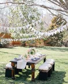 an outdoor table set up with white linens and place settings for dinner party guests