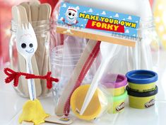 a toy fork, spoons and plastic cups on a counter with other toys in the background