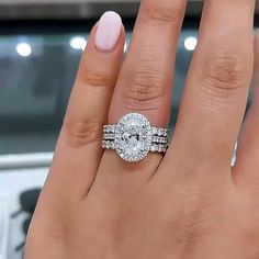 a woman's hand with two wedding rings on it and the engagement ring is in front of her