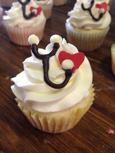 cupcakes with white frosting and black icing on a wooden table top