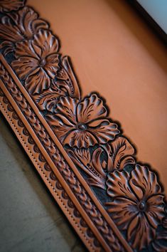 an intricately carved leather frame with flowers on it