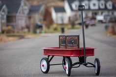 a red wagon with two boxes sitting on it's wheels in the middle of a street