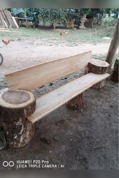 a wooden bench sitting in the middle of a dirt field next to a tree stump