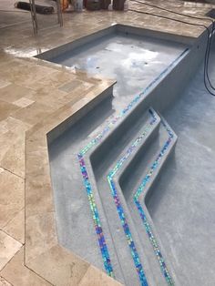 an empty swimming pool with blue and green mosaic tiles on the bottom, next to stairs