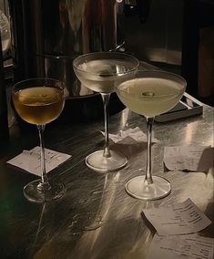 three martinis sitting on top of a counter next to each other in wine glasses