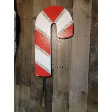 a red and white striped candy cane leaning against a wooden fence with it's end cut out