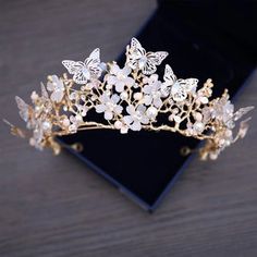 a tiara with white flowers and leaves on top of a black piece of cloth