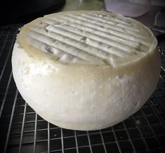 a round cheese sitting on top of a metal rack