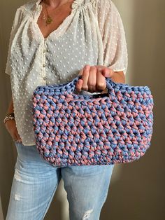 a woman holding a pink and blue purse