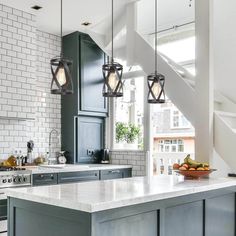 a kitchen with an island, stove and sink under some hanging lights in the ceiling