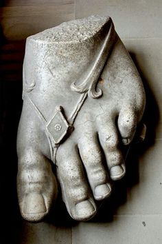 a close up of a statue of a person's foot with one hand on the ground