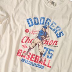 Introducing our Los Angeles Dodgers Distressed Retro Shirt, perfect for any fan! Made of 100% cotton, this unisex baseball shirt guarantees a cozy fit. For an oversized and trendy style, size up. Show your love for the Dodgers in a bold and unique way! Fabric: 100% Cotton Design: Screen Print Transfer Color: Ivory (shirt colors are pigment dyed) Colors will vary from computer to computer and monitor to monitor. The colors shown may not be an exact representation. Slight shade variations of garme Vintage Baseball Shirt, Sweatshirt Reference, Retro Baseball Shirt, Retro White T-shirt For Baseball Season, Retro Screen Print T-shirt For Baseball Season, Vintage Dodgers Shirt, Vintage Baseball Season Fan Merchandise T-shirt, Baseball Graphic Tees, Vintage Baseball Fan Merchandise T-shirt