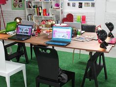 two laptops sitting on top of a wooden table in front of a book shelf