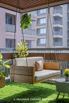 a wooden swing chair sitting on top of a green grass covered roof next to a potted plant