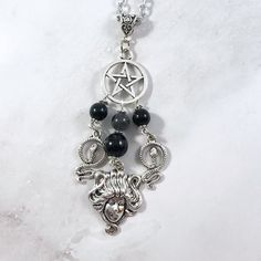 This Medusa pendant necklace is the perfect way to express your affinity for the Greek myths in subtle way. Pendant is made with four charms: Pentacle Medusa Head 2 snake charms 3 tourmaline beads and one labradorite bead also make up the pendant. Available in a variety of lengths. Chain is stainless steel, charms are zinc alloy and beads are natural gemstone. All materials are lead and nickel free. Comes in a jewelry box so it's ready to be given as a gift. Have a idea for a custom order? I'd l Spiritual Black Dangle Necklaces, Spiritual Silver Onyx Beaded Necklaces, Symbolic Black Necklace With Moon Charm, Spiritual Black Necklaces With Charms, Spiritual Silver Charm Necklaces With Gemstone Beads, Mystical Silver Gemstone Bead Necklace, Mystical Silver Necklace With Gemstone Beads, Medusa Necklace, Medusa Pendant