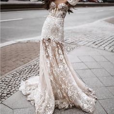 a woman is standing on the sidewalk with an umbrella in her hand and wearing a wedding dress