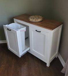 a white cabinet with two bins and a wooden counter top that has a plate on it