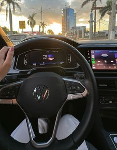 the interior of a car with touchscreens, steering wheel controls and palm trees in the background