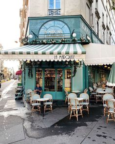 an outdoor cafe with tables and chairs in front of it on the side of the street