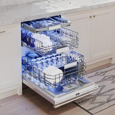 an open dishwasher in a kitchen with white cabinets and counter tops on the floor