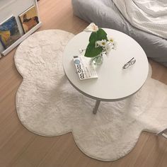 a white table sitting on top of a hard wood floor next to a chair and bed