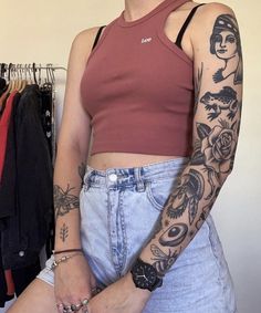 a woman with tattoos on her arm standing next to a rack of clothes