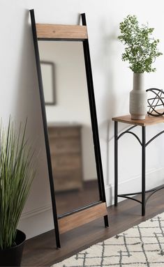 a mirror sitting on top of a wooden table next to a potted plant