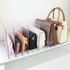 several purses are lined up on a shelf with clear acrylic holders for them